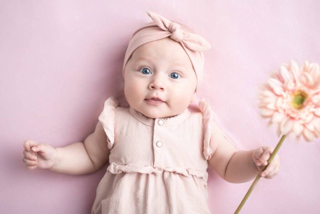 Wunderschönes Baby mit Blume in der Hand bei einem Meilenstein Fotoshooting von Siebenschön Photography in der Nähe von Ahlen