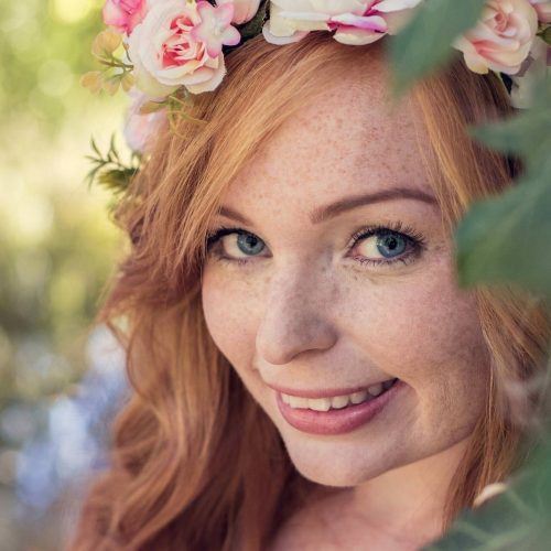 Portraitfoto einer wunderschönen Frau mit roten Haaren und einem Blumenkranz fotografiert von Siebenschön Photography im Kreis Warendorf